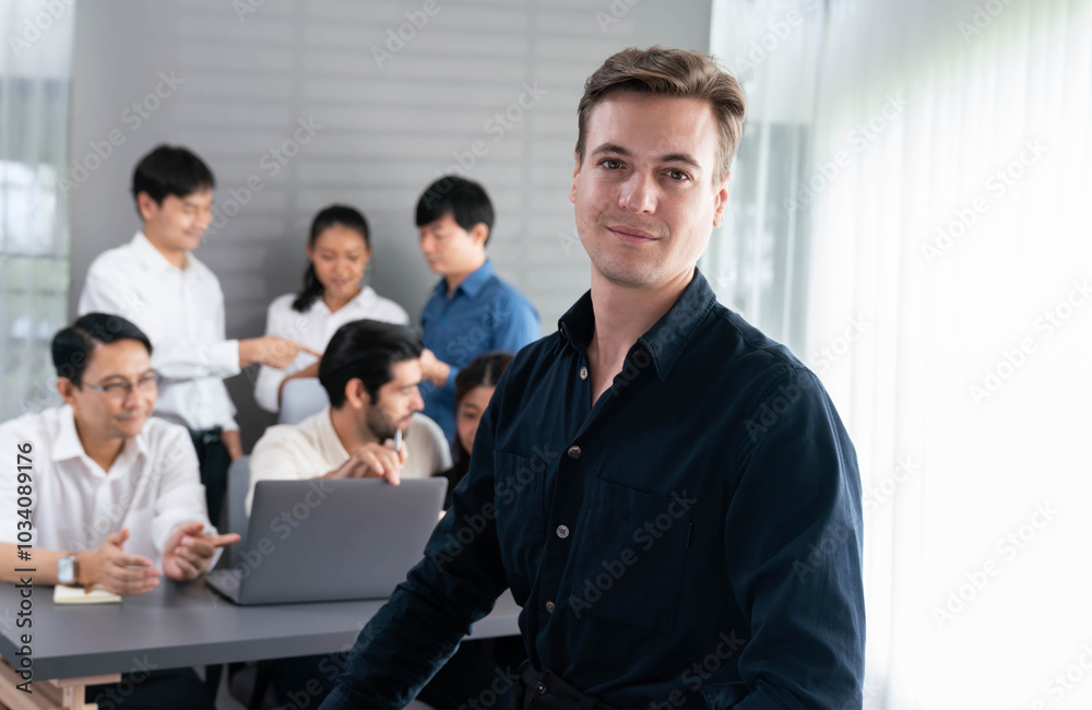 Confidence and happy smiling businessman portrait with background of his colleague and business team working in office. Office worker teamwork and positive workplace concept. Prudent Confidence and happy smiling businessman portrait with background of his colleague and business team working in office. Office worker teamwork and positive workplace concept. Prudent