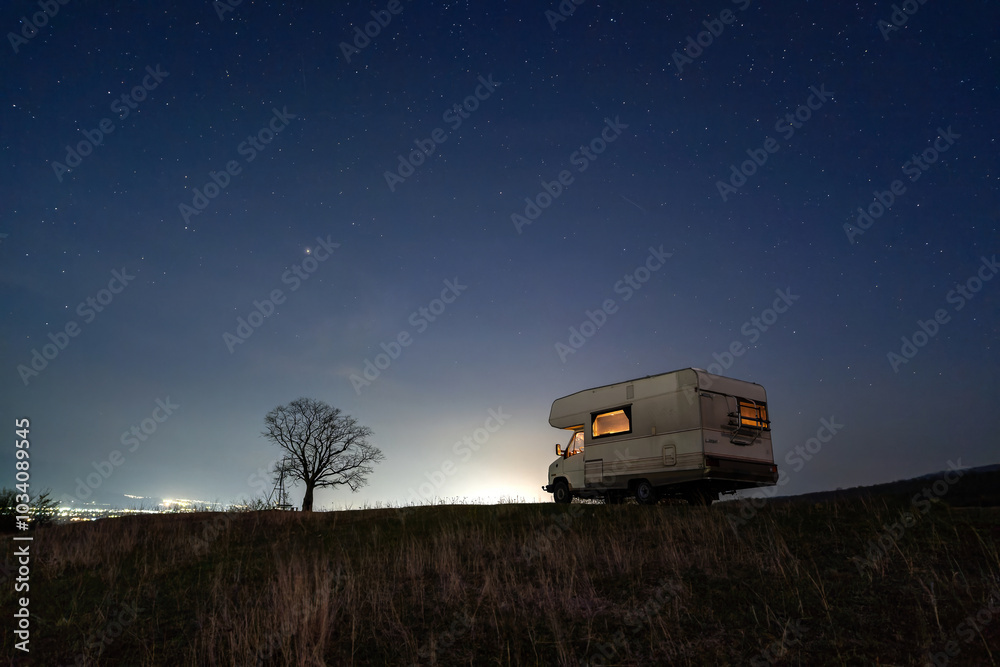 Motorhome camping in the mountains at night, under the starry sky Motorhome camping in the mountains at night, under the starry sky