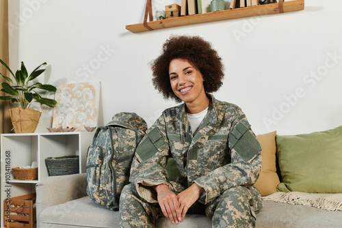 A young woman in military attire sits comfortably in her living room, preparing for her upcoming service.