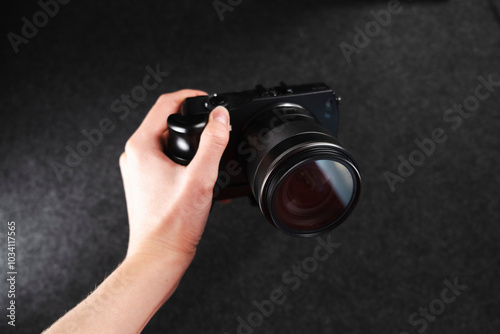 Black digital camera. Camera in hands. Camera on black background. Gray background. Modern technologies. Photographer. Camera body. Lens photo