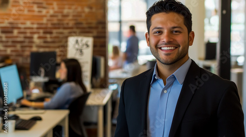 An attractive man in his late thirties, dressed for business with black blazer and blue shirt, smiling at the camera.