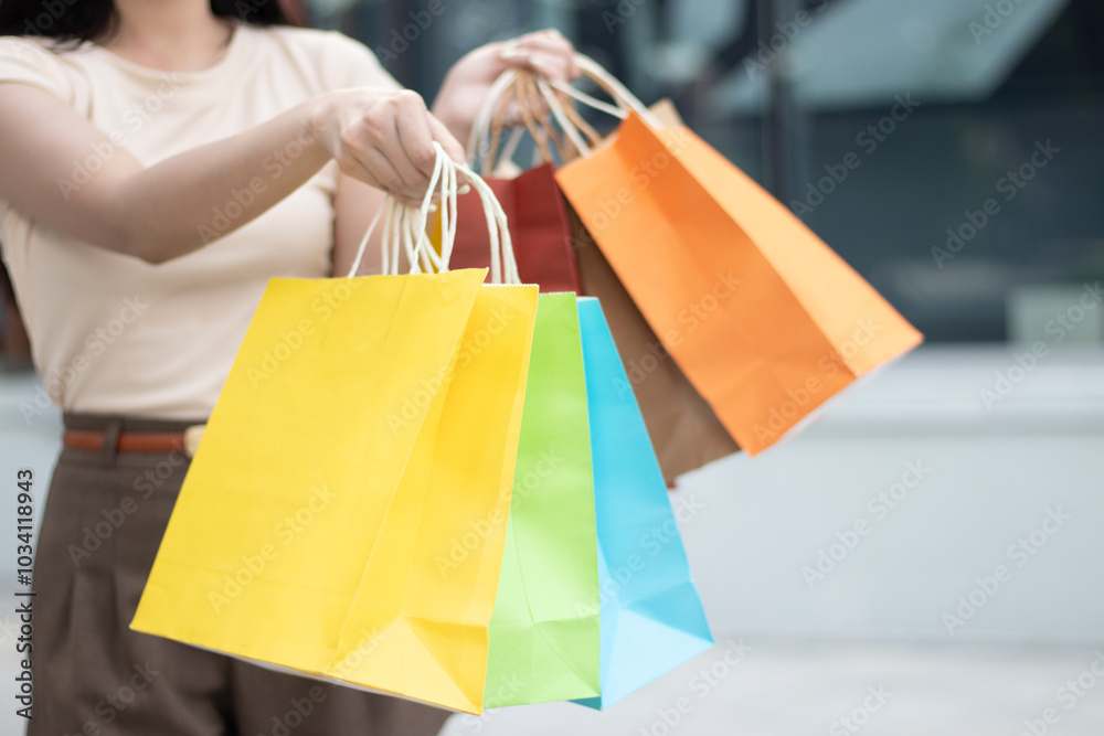 Young middle-aged Asian woman using a cell phone and carrying shopping bags outside her home on a city street. Young middle-aged Asian woman using a cell phone and carrying shopping bags outside her home on a city street.
