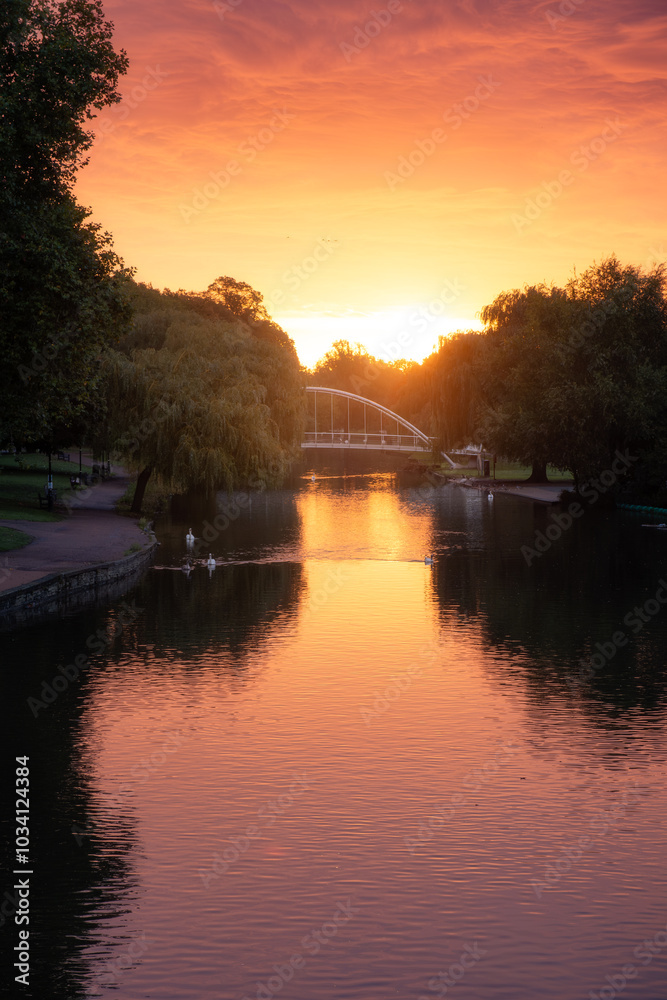 Fototapeta premium Sunrise behind the Butterfly Bridge passing over the River Great Ouse on the Embankment at Bedford, England