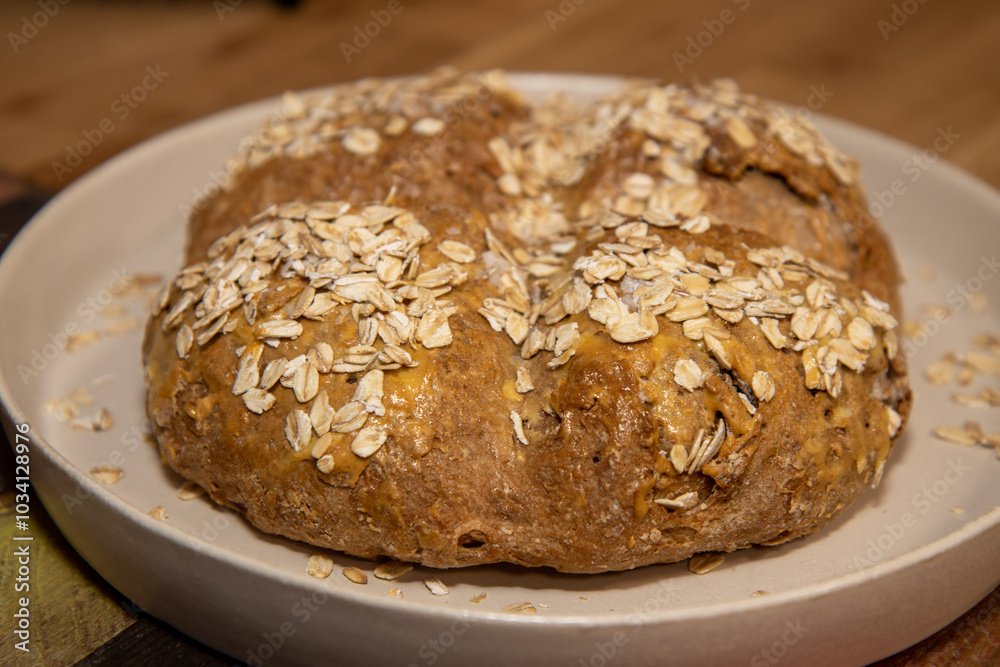 A round home baked bread roll covered in seeds on a white plate A round home baked bread roll covered in seeds on a white plate