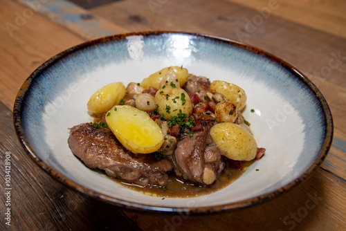 A delicious plate of chicken coq au vin with potatoes on a wooden kitchen work top photo