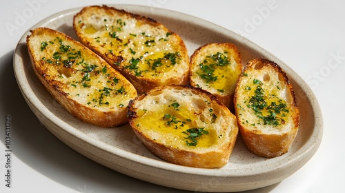 Garlic bread with olive oil on a white plate, against a table background.