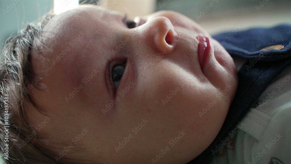 Close-up of a baby lying on their back with an inquisitive expression, gazing upwards with wide eyes. natural lighting highlights the soft textures of the baby’s face and skin Close-up of a baby lying on their back with an inquisitive expression, gazing upwards with wide eyes. natural lighting highlights the soft textures of the baby’s face and skin