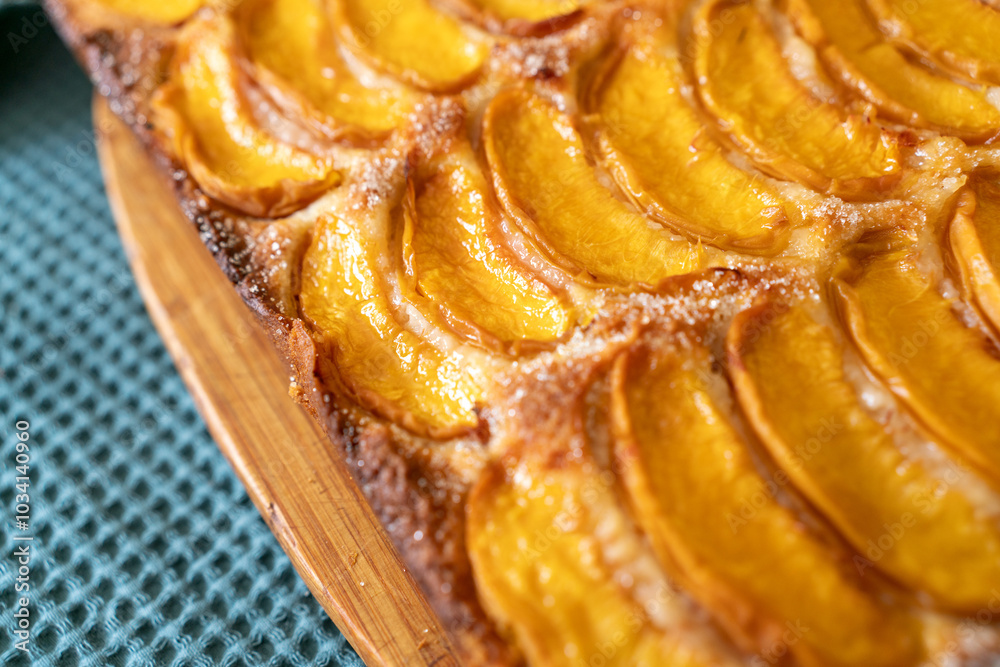 A dessert made of sliced peaches is on a wooden cutting board. The dessert is covered in sugar and looks delicious. A dessert made of sliced peaches is on a wooden cutting board. The dessert is covered in sugar and looks delicious.