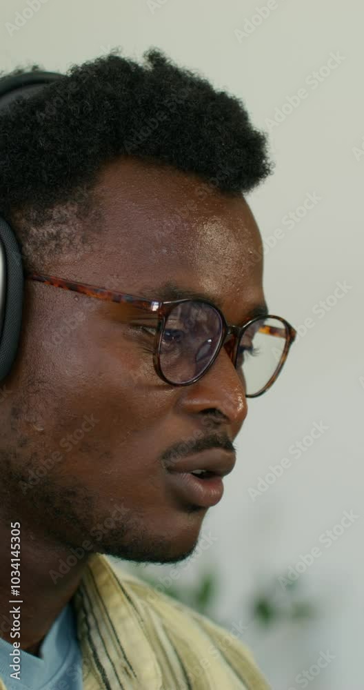 A man with headphones is smiling while talking on a video chat. He's at home. close-up of his face. Daylight A man with headphones is smiling while talking on a video chat. He's at home. close-up of his face. Daylight