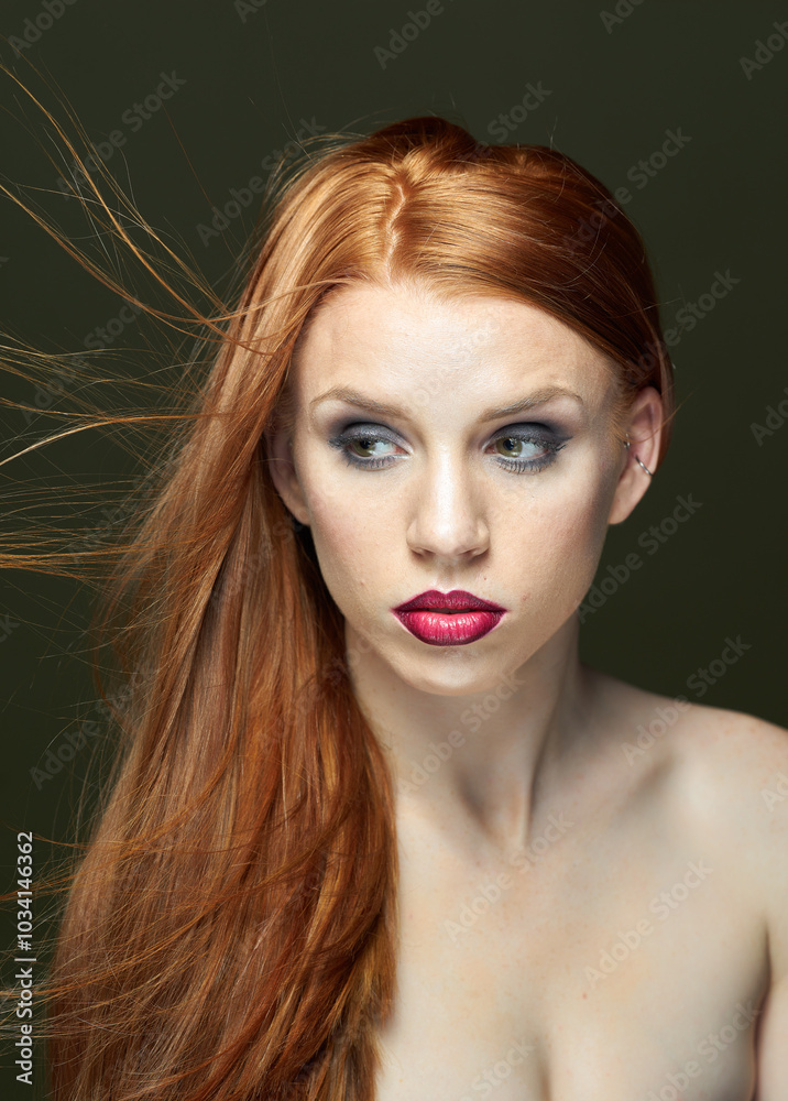 Fototapeta premium Woman with red hair and red lipstick poses for a photo. She has thick, beautiful hair. Fashion and beauty concept.