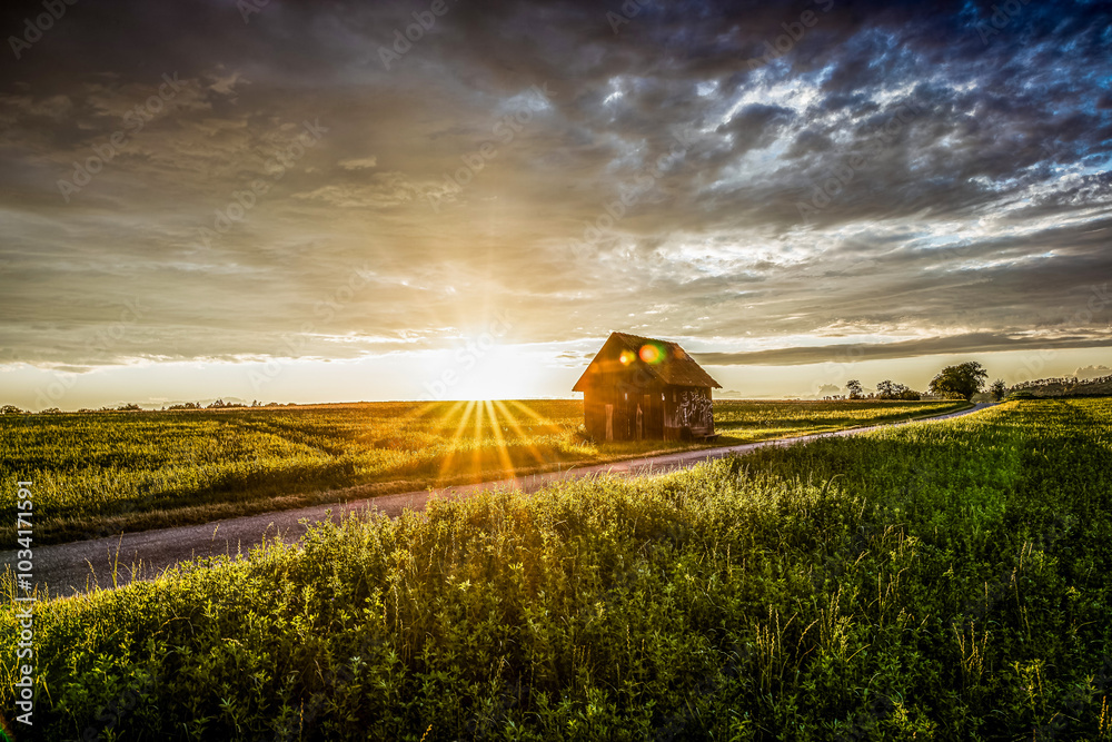 Fototapeta premium die Sonne geht hinter einer kleinen Hütte unter