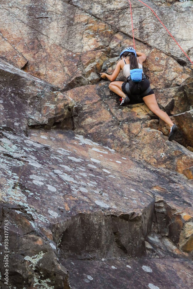 Image of a fit and attractive brunette girl climbing a granite rock wall Image of a fit and attractive brunette girl climbing a granite rock wall