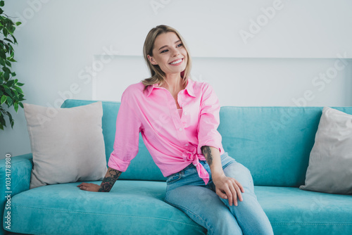 Young woman relaxing on a sofa at home, enjoying leisure time in a bright living room