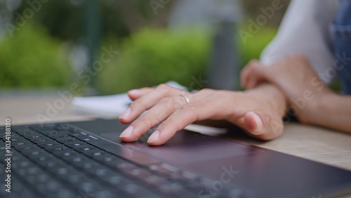 Girl hands using touchpad laptop at street cafe closeup. Unknown woman fingers 