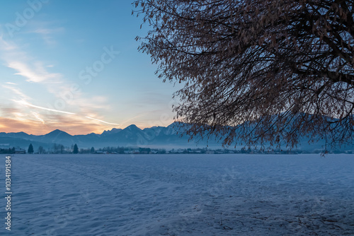 Snow covered field with scenic sunrise view of majestic snow-capped mountain range in Karawanks seen from Rosental, Carinthia, Austria. Peaceful alpine landscape. Tranquil winter scene Austrian Alps photo