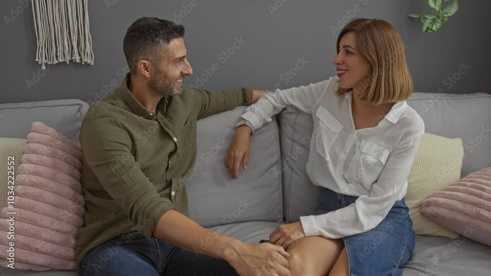 Man and woman sitting together on a cozy sofa in a well-decorated living room, sharing a heartfelt conversation and embrace, expressing love and affection in a home setting Man and woman sitting together on a cozy sofa in a well-decorated living room, sharing a heartfelt conversation and embrace, expressing love and affection in a home setting