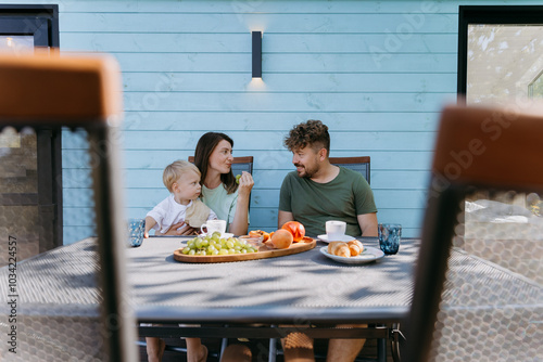 Family enjoying breakfast together on a sunny morning, with fresh fruits and coffee outdoors photo