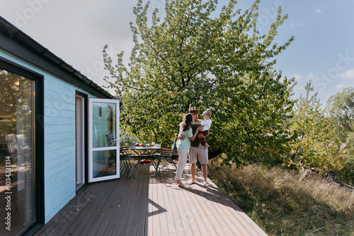 Happy family enjoying a peaceful outdoor moment on a wooden deck, surrounded by nature and sunshine photo