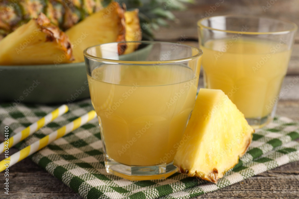 Tasty pineapple juice in glasses and slice of fresh fruit on wooden table, closeup Tasty pineapple juice in glasses and slice of fresh fruit on wooden table, closeup