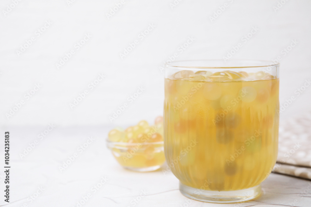 Tasty bubble tea in glass and tapioca pearls on white table, closeup. Space for text Tasty bubble tea in glass and tapioca pearls on white table, closeup. Space for text