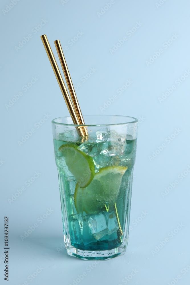 Tasty refreshing drink with straws in glass on light blue background Tasty refreshing drink with straws in glass on light blue background