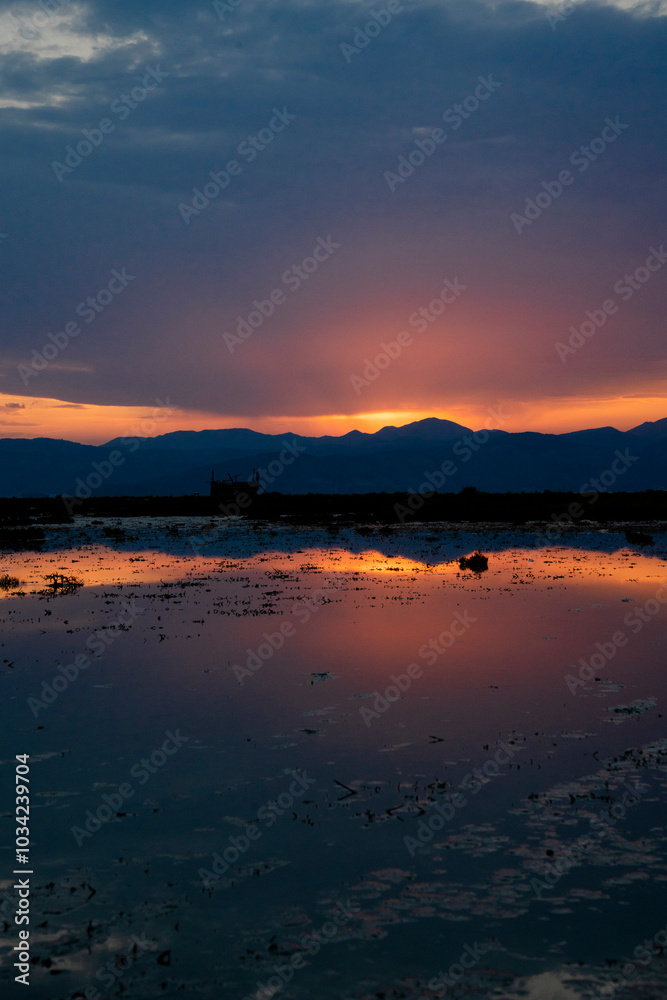 Riflesso di un alba su una laguna con montagne sullo sfondo Riflesso di un alba su una laguna con montagne sullo sfondo