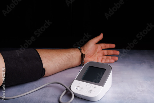 Close-up of a person using a digital blood pressure monitor on a concrete table, showcasing heart health and wellness in a medical setting