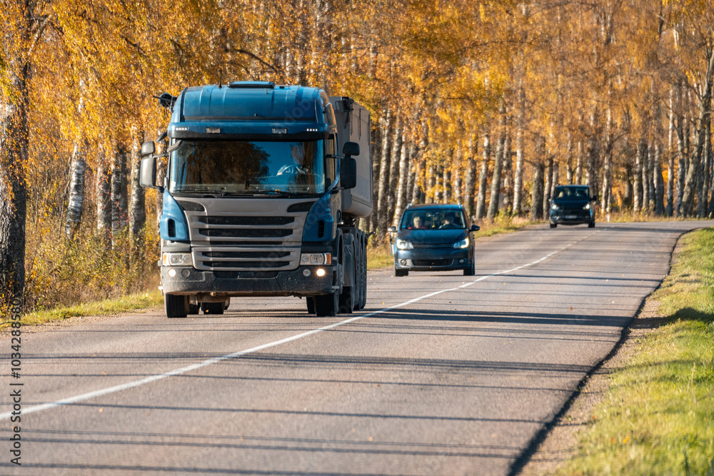 Obraz premium Truck on autumn highway. A truck carrying gravel on a highway on autumn day.