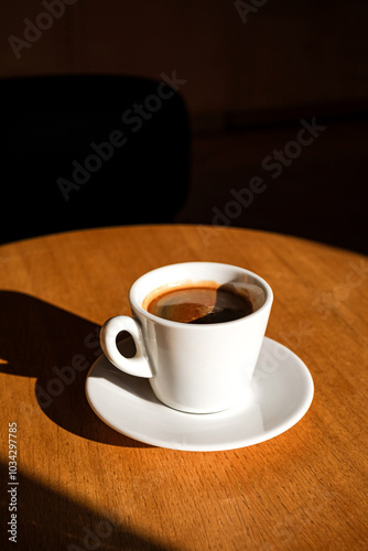 A cup of black coffee on the table in the sunlight