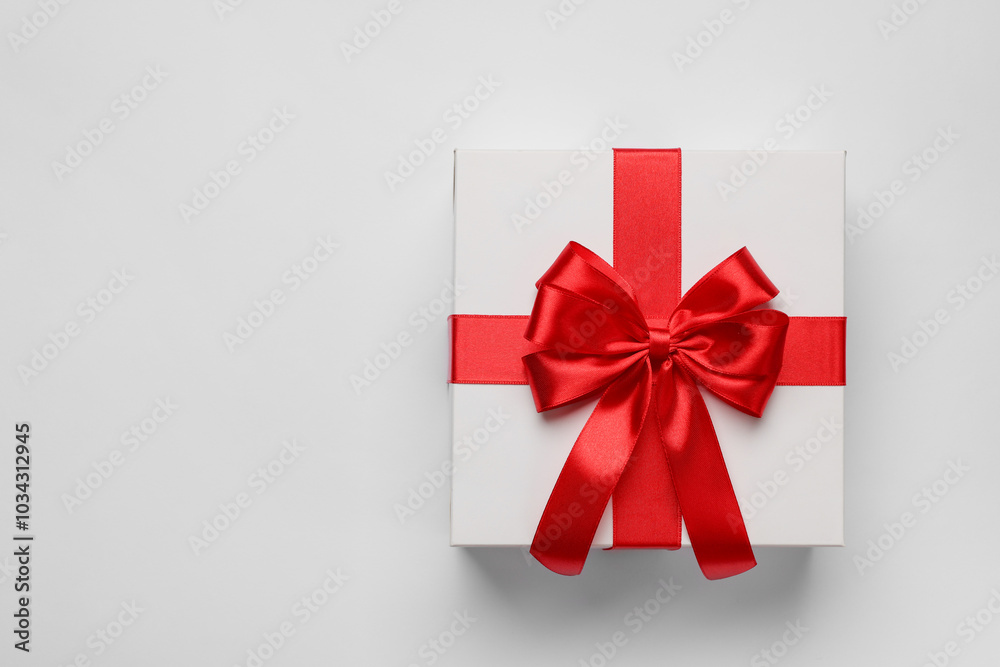 Gift box with red bow on light grey background, top view. Space for text