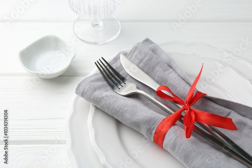 Stylish plates, cutlery, napkin, sauce bowl and glass on white wooden table, closeup photo