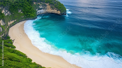 A stunning aerial shot of the turquoise waves gently crashing onto the soft sands of Kelingking Beach, Nusa Penida, Bali. The vibrant colors highlight the serenity and beauty of this tropical paradise