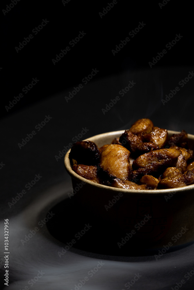 Fried chicken in a cardboard container on a black background in the shade with smoke Fried chicken in a cardboard container on a black background in the shade with smoke
