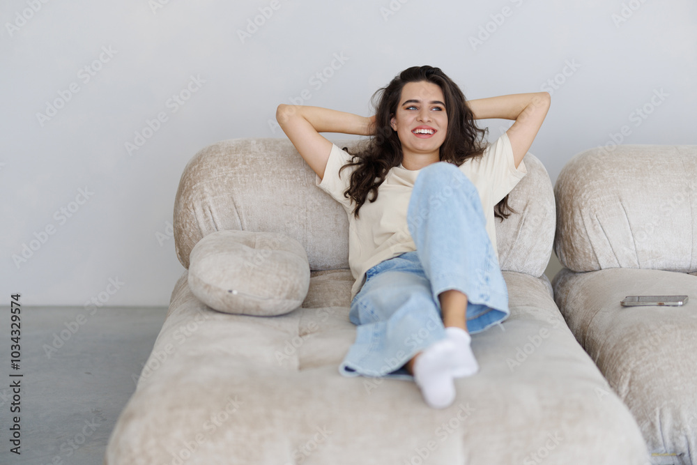 Kick back and relax concept. Young woman with blissful facial expression alone on the couch. Kick back and relax concept. Young woman with blissful facial expression alone on the couch.