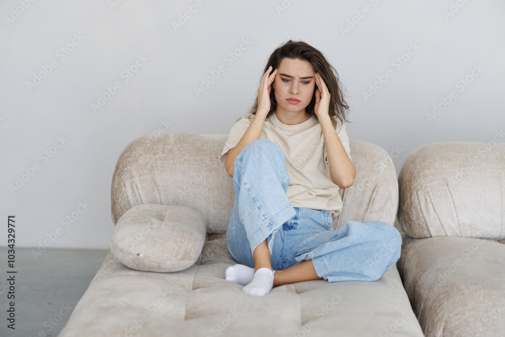 Stressed young woman suffering migraine and complaining sitting on a couch at home Stressed young woman suffering migraine and complaining sitting on a couch at home