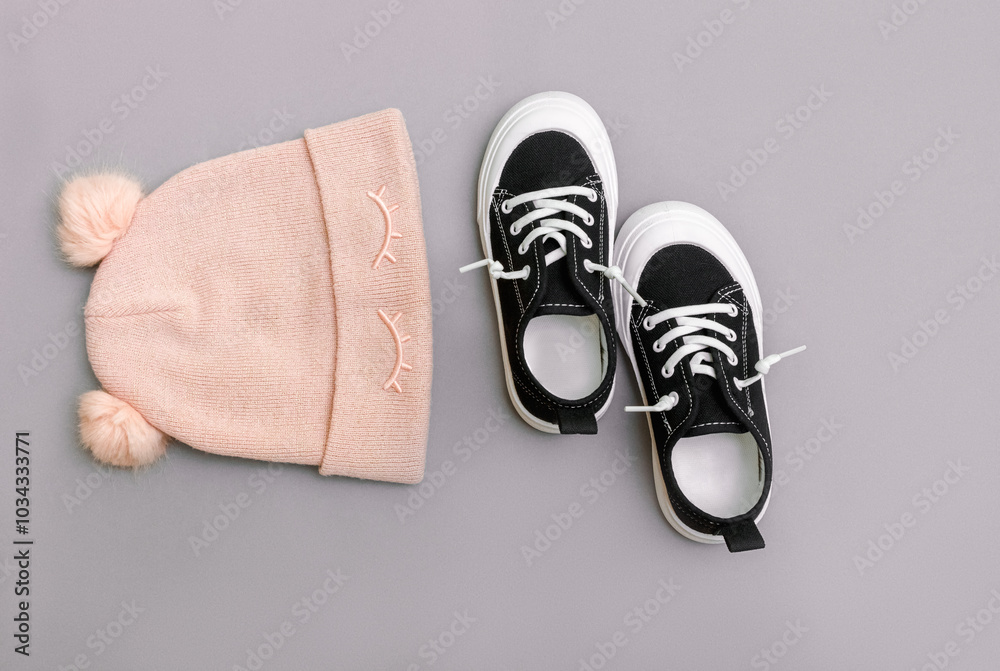 Kids clothing. Knitted hat with cneakers on the grey background. Top view. Fashion concept. Child girl's autumn clothes