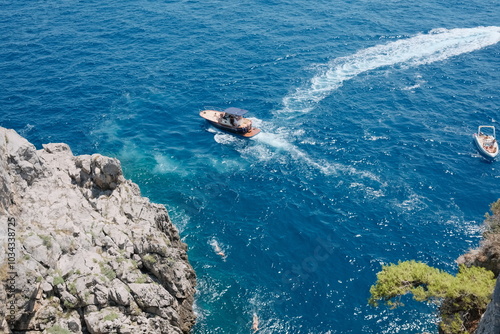 Wallpaper Mural A boat glides through the sparkling blue waters along the Amalfi Coast, Italy, framed by rugged cliffs and lush greenery, highlighting the stunning Mediterranean seascape. Torontodigital.ca