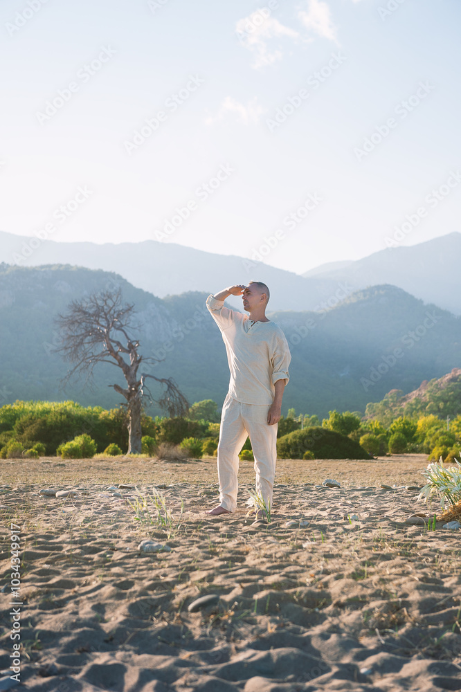 Obraz premium Man meditates barefoot in a vast desert landscape surrounded by mountains