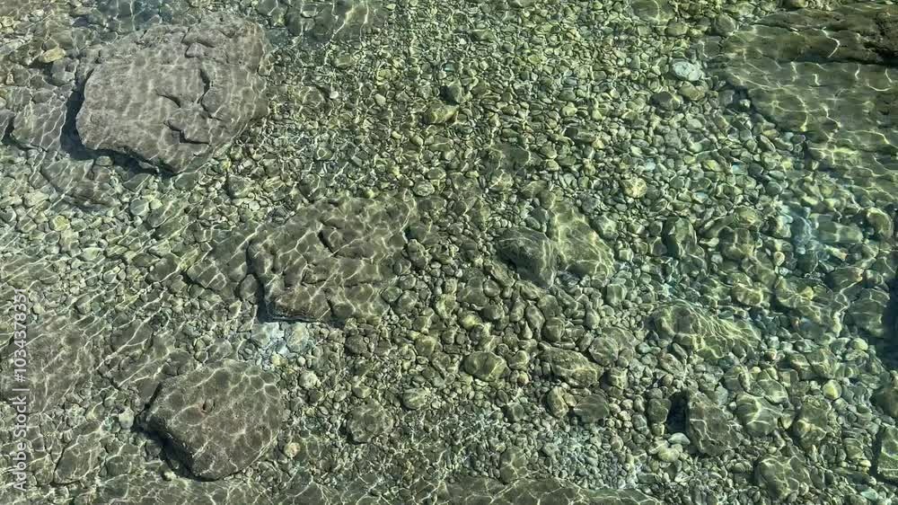 Sea water calm transparent surface with pebbles at the bottom. Sea water calm transparent surface with pebbles at the bottom.