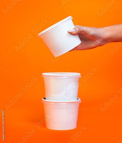 Foto Hand holding white packaging recipients for ice cream on colored background