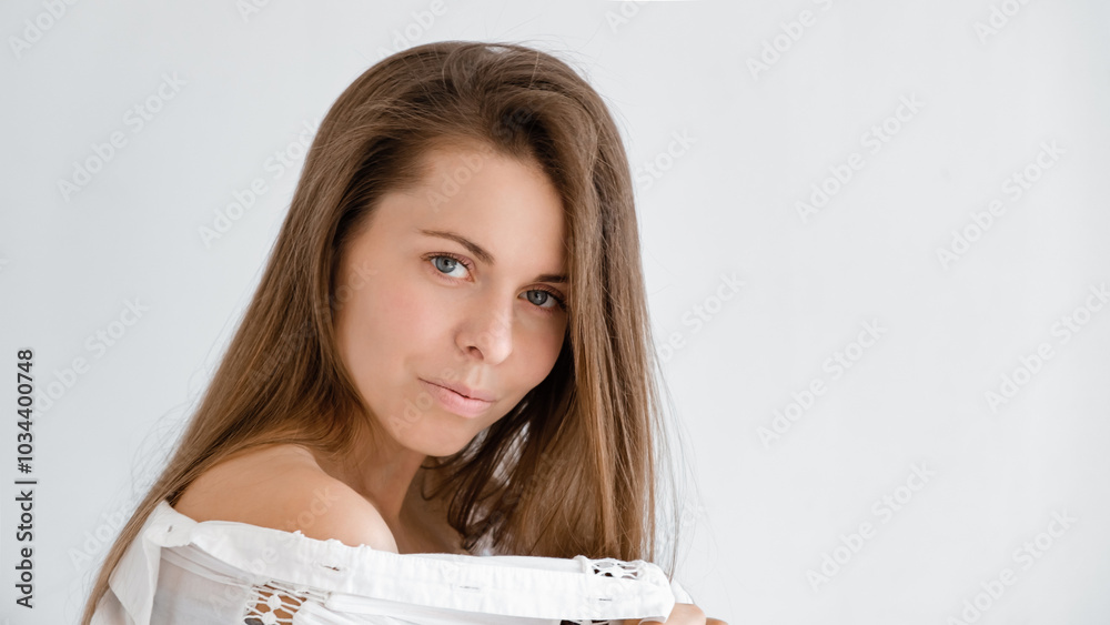 Pretty 30s woman looking at camera in white top shirt exposing shoulder. Studio portrait. Boho style dress. Natural beauty face. Concept of tenderness and femininity. Flirting look Pretty 30s woman looking at camera in white top shirt exposing shoulder. Studio portrait. Boho style dress. Natural beauty face. Concept of tenderness and femininity. Flirting look