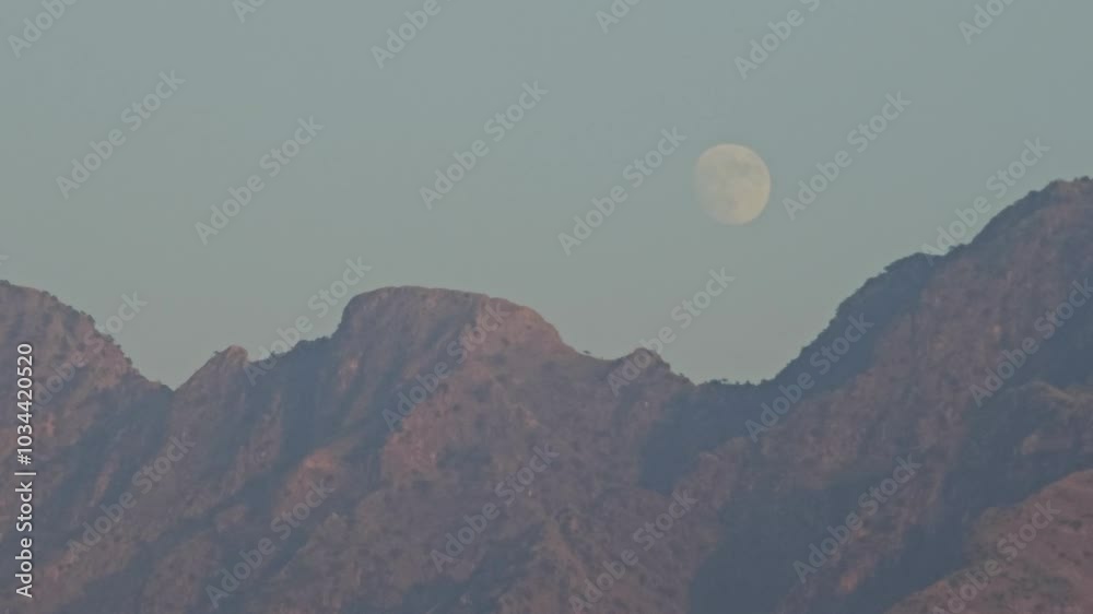 SUPERMOON WITH MOONLIGHT RISING IN EVENING BEHIND HUGE MOUNTAINS AND CLEAR BLUE SKY DURING DUSK SUPERMOON WITH MOONLIGHT RISING IN EVENING BEHIND HUGE MOUNTAINS AND CLEAR BLUE SKY DURING DUSK