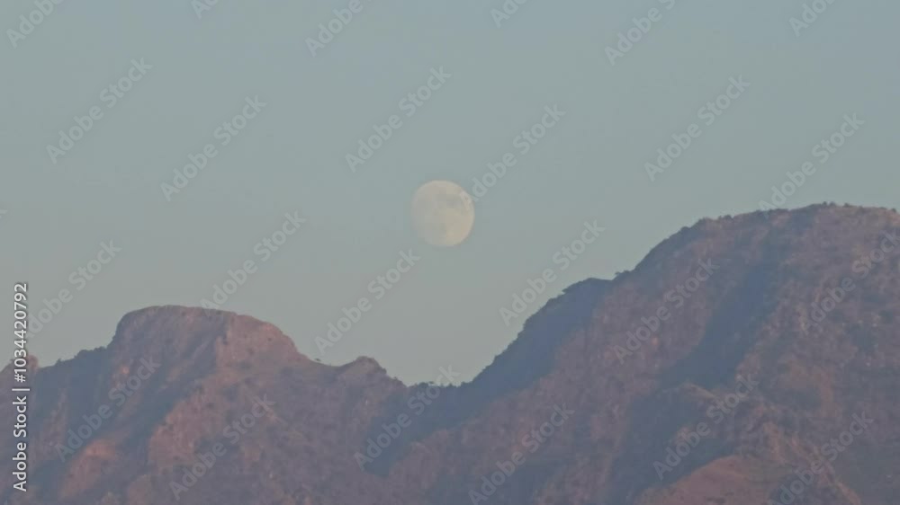 SUPERMOON WITH MOONLIGHT RISING IN EVENING BEHIND HUGE MOUNTAINS AND CLEAR BLUE SKY DURING DUSK SUPERMOON WITH MOONLIGHT RISING IN EVENING BEHIND HUGE MOUNTAINS AND CLEAR BLUE SKY DURING DUSK
