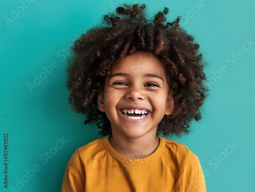 Joyful child laughing with curly hair on teal background