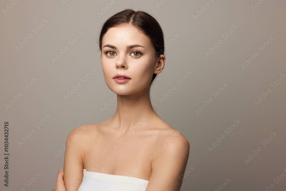 Beautiful young woman posing with arms crossed on gray background Beautiful young woman posing with arms crossed on gray background