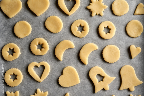 Shapes made of raw pastry dough on baking paper - preparation of Linzer Christmas cookies