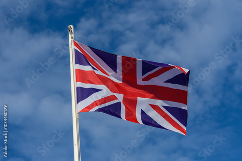 Union Jack flag waving against a clear blue sky during a sunny day in the United Kingdom, showcasing national pride and heritage photo