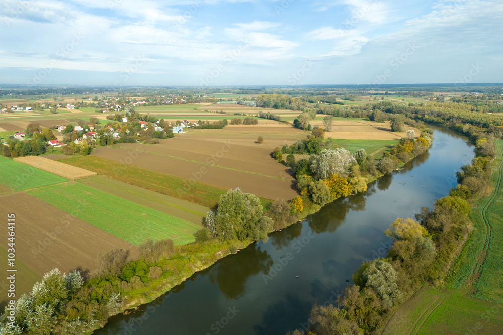 Aerial view of lush green fields and a winding river surrounded by trees and farmland. The serene landscape captures the beauty of nature in its purest form. Aerial view of lush green fields and a winding river surrounded by trees and farmland. The serene landscape captures the beauty of nature in its purest form.