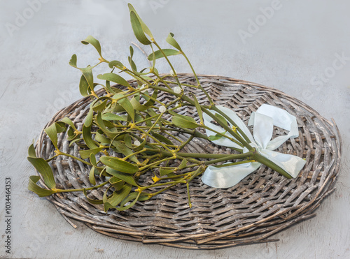 Cut sprig of mistletoe leaves with berries on a wicker circle for home decoration for Christmas.