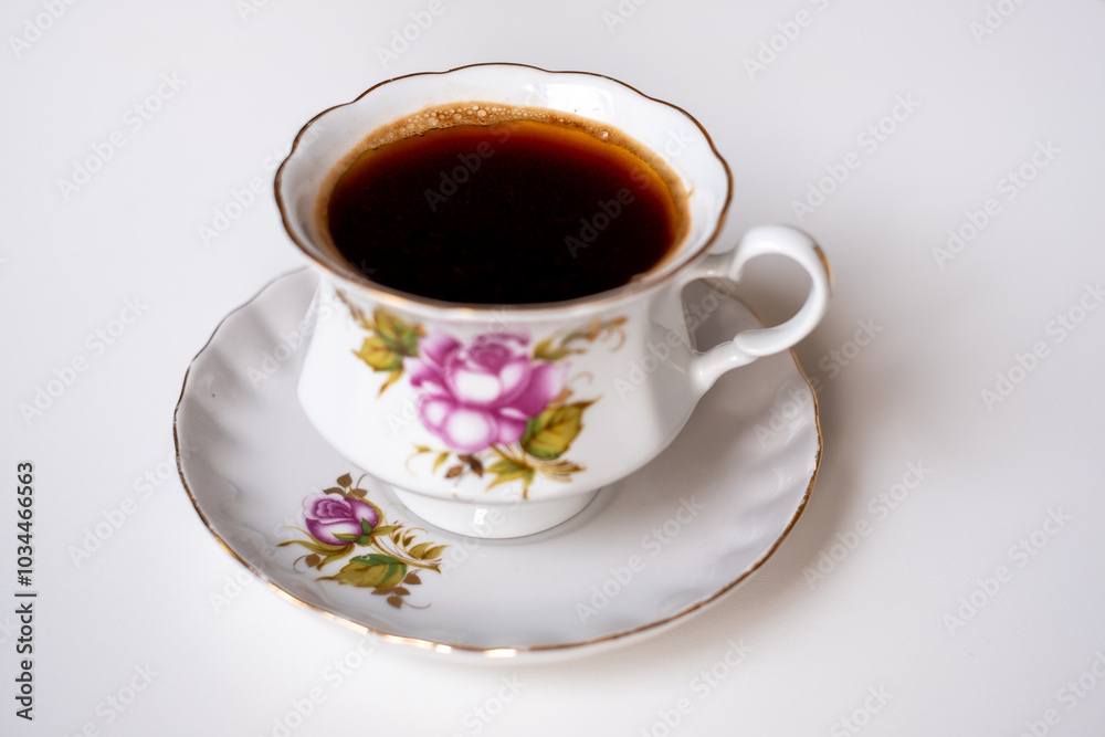 A delicate porcelain cup of coffee on a matching saucer featuring floral designs, perfect for a quiet morning A delicate porcelain cup of coffee on a matching saucer featuring floral designs, perfect for a quiet morning